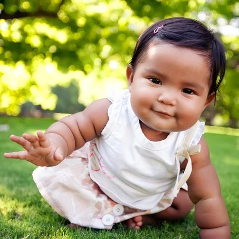 Image of a baby sitting on the grass.