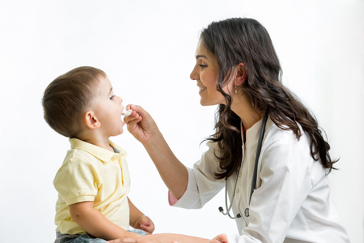 Doctor giving child patient medicine.